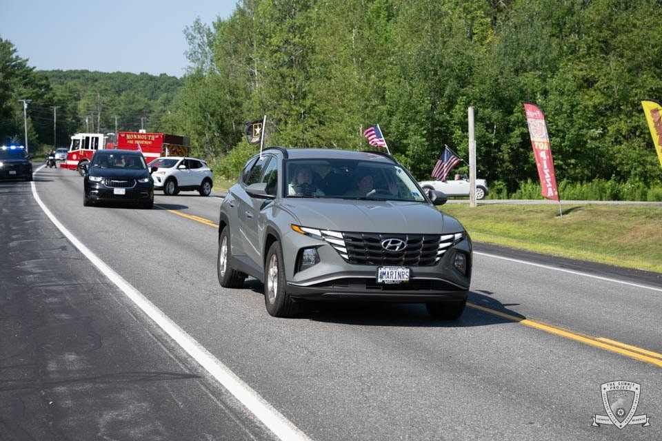 A Hyundai Tucson with a #MARINRS plate and American flags rolls through the 2026 procession.