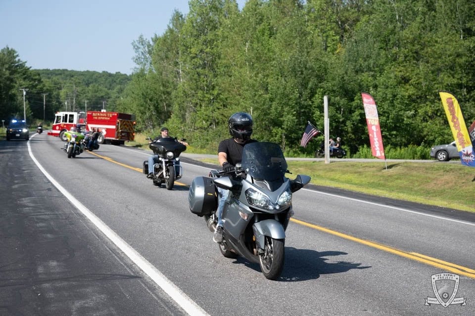 A sport-touring bike leads the pack with riders and the Monmouth FD truck filling the road behind.