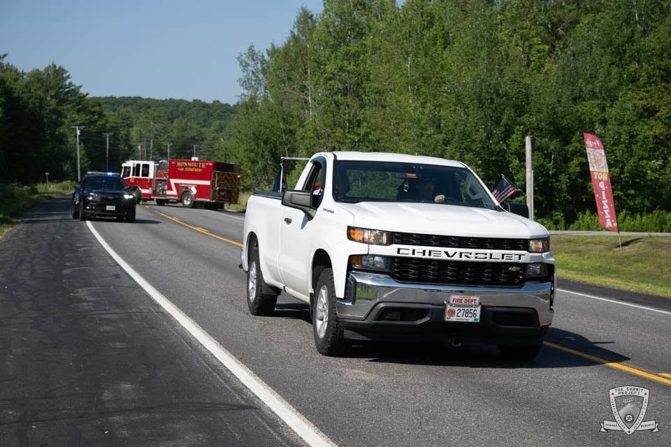 A white Chevrolet Silverado with Fire Dept plates rolls through the 2026 procession.