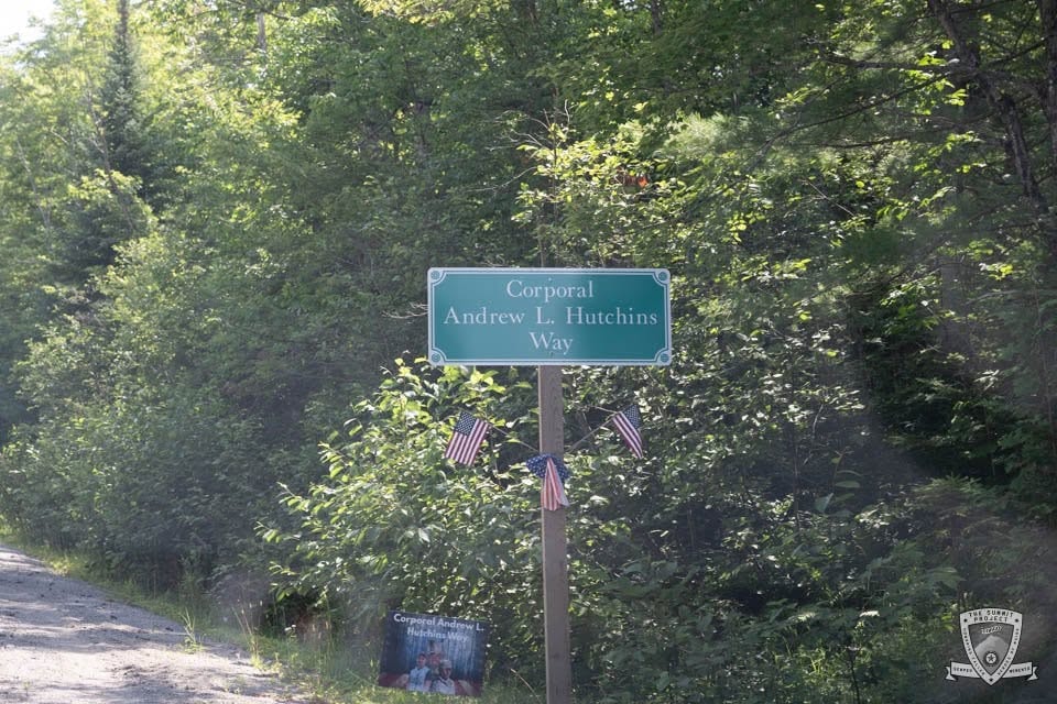 The "Corporal Andrew L. Hutchins Way" street sign, adorned with American flags, marks the road named in his honor.