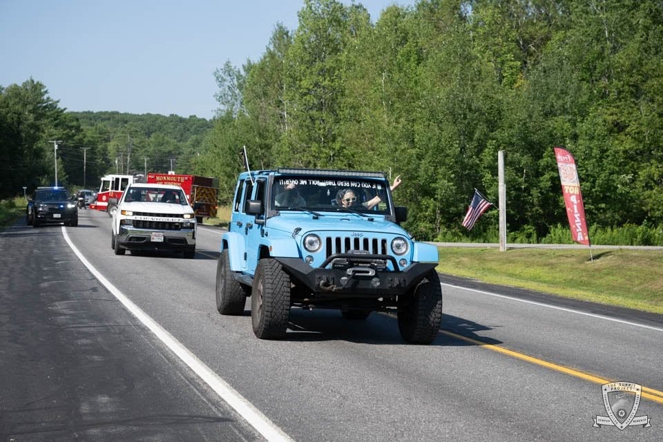 A blue Jeep leads a line of vehicles along the 2026 route.
