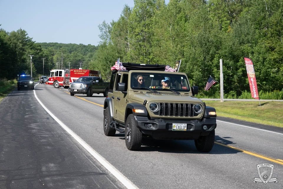 An olive Jeep decorated with American flags and flowers rolls through the 2026 procession.